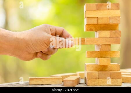 Nahaufnahme der Hand Bausteine holding Holz Spiel auf verschwommen grünen Hintergrund. Kopieren mit Platz für Text oder Design Konzept Stockfoto