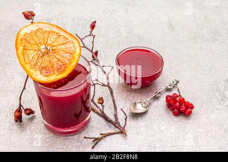 Natürliche frische organische Smoothies und Marmelade aus Viburnum, Wildrose und Grapefruit. In einem Glas auf steinernem Grund. Hunderose, getrocknete Grapefruit Stockfoto