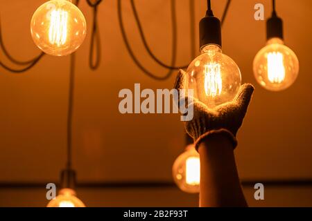 Asiatischer Mann/Hausbesitzer, der alte Glühbirne putzen oder auswechseln soll. Hauswartungskonzept Stockfoto