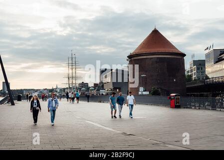 Hamburg, Deutschland - 4. August 2019: Menschen, die im Sommer bei Sonnenuntergang im Hamburger Hafen auf der Promenade spazieren Stockfoto