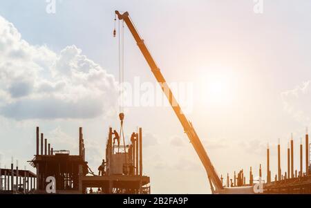 Silhouette des Bauarbeiters, der vor Ort für die Dachkonstruktion im Prozess des Hausbaus arbeitet Stockfoto