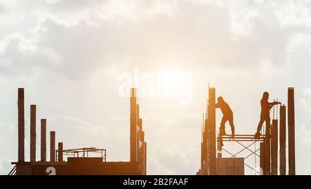 Silhouette des Bauarbeiters, der vor Ort für die Dachkonstruktion im Prozess des Hausbaus arbeitet Stockfoto