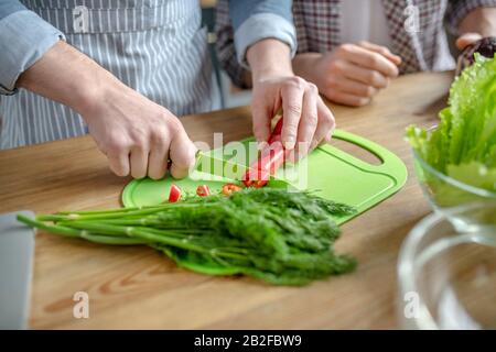 Nahaufnahme von Männern Hände schneiden Gemüse Stockfoto