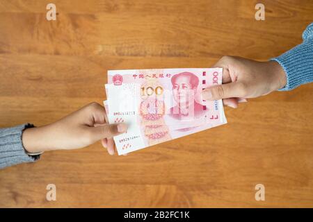Verleihen oder Geben von Geld Konzept. Hand in der Draufsicht mit Banknotenwährung Chinese Yuan (CNY oder RMB) für Immobilien- und Landgeschäfte Stockfoto