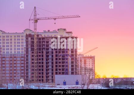 Wintermorgen der Bau von mehrstöckigen Rahmenhäusern mit Turmkränen, eisige Bauweise Stockfoto