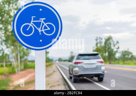 Moderner SUV-Wagen, der auf Asphaltstraße/Fahrradspur läuft und auf weißem Fahrradschild fährt Stockfoto