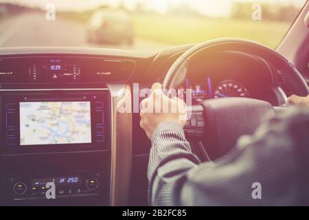 Mann fährt modernes SUV-Auto auf der Straße. Das Lenkrad in die Hand nehmen. Ansicht von der Rückseite Stockfoto