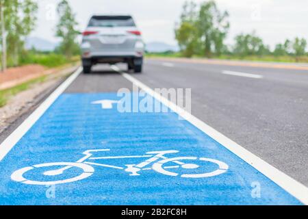 Moderner SUV-Wagen, der auf Asphaltstraße/Fahrradspur läuft und auf weißem Fahrradschild fährt Stockfoto