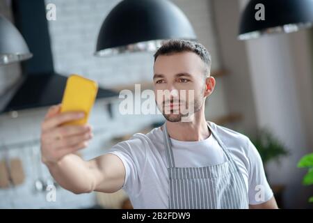 Junger Mann mit gelbem Smartphone in der Hand. Stockfoto