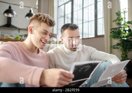 Zwei glückliche junge Männer, die sich Bilder von Ultraschall ansehen. Stockfoto