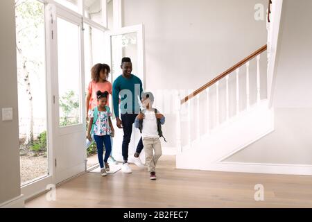 Vorderansicht eines afroamerikanischen Paares mit jungen Sohn und Tochter, das in die Haustür ihres neuen Hauses eindringt. Familie genießt Zeit zu Hause, lebensfreude Stockfoto