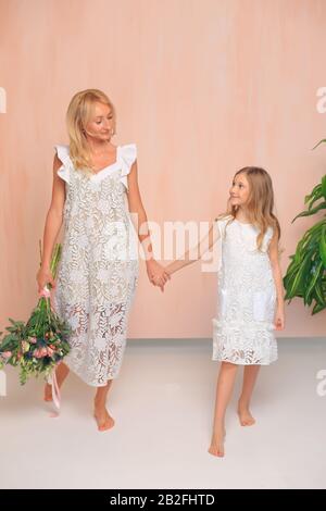 Mama mit ihrer Tochter in weißen Kleidern im Studio. Stockfoto