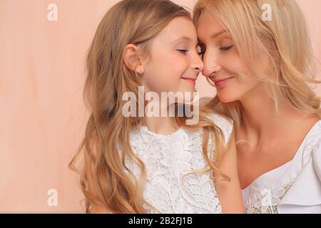 Mama mit ihrer Tochter in weißen Kleidern im Studio. Stockfoto