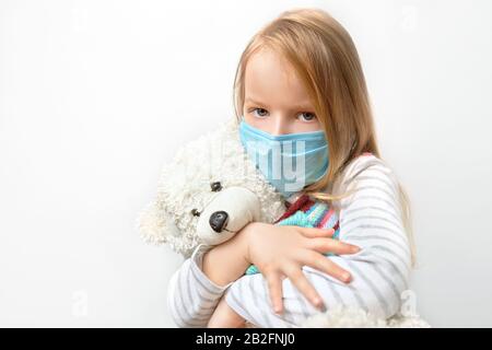 Coronavirus Kovid-19 und Umweltschutzkonzept: Kleines Kindermädchen umarmt Teddybärpuppe mit Tragemaske gegen Corona-Virus und Luft Stockfoto