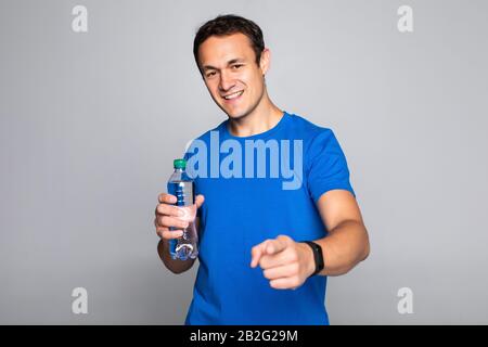 Schöne Fitness Mann mit Handtuch und eine Flasche mit Wasser isoliert auf einem weißen Hintergrund. Blick in die Kamera Stockfoto