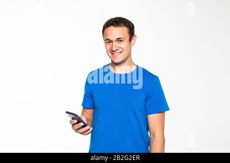 Bild eines jungen, unrasierten Mannes in Sportbekleidung, der über grauem Hintergrund isoliert posiert und das Handy benutzt Stockfoto