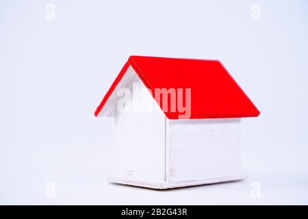 Finanzklage - Piggy Bank, wunderschönes rot-weißes Holzhausmodell auf weißem Hintergrund, spart Geld beim Kauf von Versicherungen, Nahaufnahme, Kopierplatz. Stockfoto