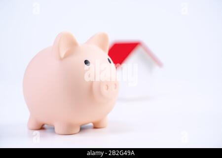 Finanzklage - Piggy Bank, wunderschönes rot-weißes Holzhausmodell auf weißem Hintergrund, spart Geld beim Kauf von Versicherungen, Nahaufnahme, Kopierplatz. Stockfoto