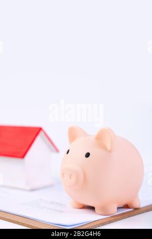 Finanzklage - Piggy Bank, wunderschönes rot-weißes Holzhausmodell auf weißem Hintergrund, spart Geld beim Kauf von Versicherungen, Nahaufnahme, Kopierplatz. Stockfoto