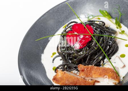 Frische schwarze Tagliolini-Pasta mit Huhn in Kräutern Stockfoto