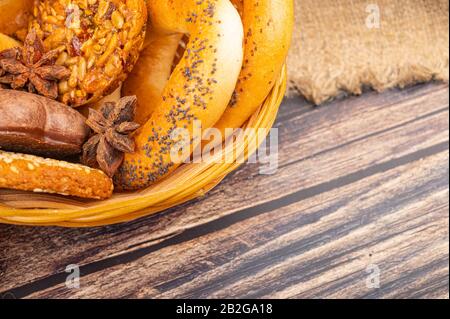 Plätzchen, Schokoladenkuchen und Bagels in einem Korbkorb auf Holzgrund. Nahaufnahme Stockfoto