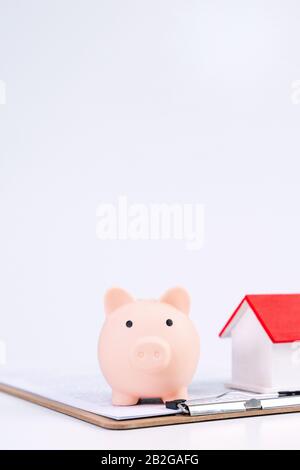 Finanzklage - Piggy Bank, wunderschönes rot-weißes Holzhausmodell auf weißem Hintergrund, spart Geld beim Kauf von Versicherungen, Nahaufnahme, Kopierplatz. Stockfoto
