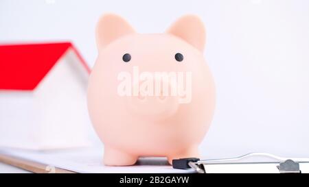 Finanzklage - Piggy Bank, wunderschönes rot-weißes Holzhausmodell auf weißem Hintergrund, spart Geld beim Kauf von Versicherungen, Nahaufnahme, Kopierplatz. Stockfoto