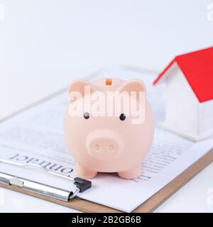 Finanzklage - Piggy Bank, wunderschönes rot-weißes Holzhausmodell auf weißem Hintergrund, spart Geld beim Kauf von Versicherungen, Nahaufnahme, Kopierplatz. Stockfoto