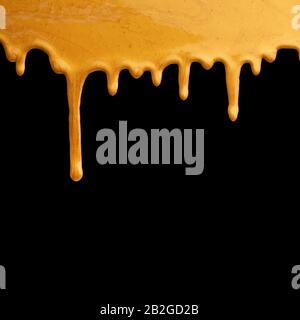 Goldfarbe tropft auf schwarzem Hintergrund, kreativer Rahmen Stockfoto