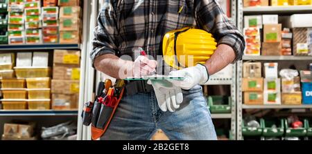 Elektrofachkraft im Elektrogerätelager schreibt auf dem Notebook. Bauindustrie, Elektrik. Stockfoto