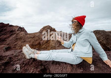 Junge Reisende, die sich auf dem felsigen Land ausruhen und vulkanische Landschaften am Meeresufer nahe dem Leuchtturm unterwegs sind Stockfoto