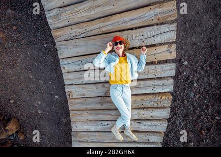 Porträt einer jungen, stilvollen Frau, die in hellen Kleidern auf dem Holzweg im Freien gekleidet ist Stockfoto