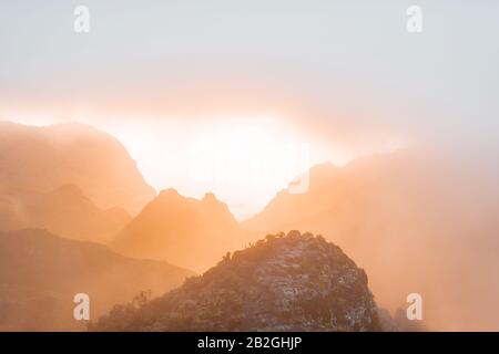 Atemberaubende Landschaft auf der Bergkette unter den Wolken und dem Meer im Hintergrund bei Sonnenuntergang Stockfoto