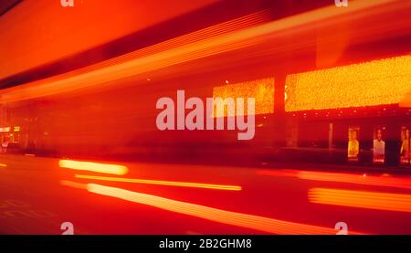 City Street in der Nacht mit verschwommener schneller Autobeleuchtung. Rotes und gelbes Licht an der Stange neben dem Gebäude. Abstrakter Hintergrund für Nachtlicht. Unschärfe Stockfoto