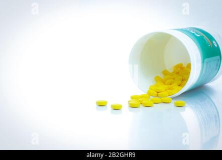 Gelbe Tablettenpillen verteilen sich aus der Medikamentenflasche. Tabletts Tabletten mit Flasche auf weißem Tisch. Medikamentenproduktion im Konzept der pharmazeutischen Industrie. Gesundheit. Stockfoto