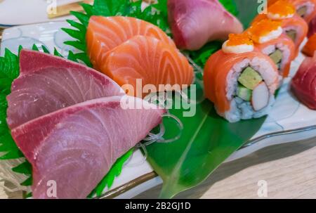 Japanisches Essen auf weißem Teller serviert. Lachssushi und Sashimi auf Restauranttisch. Frisches rohes Fischfleisch in Scheiben und Japan vinegared Reisrollen mit Stockfoto