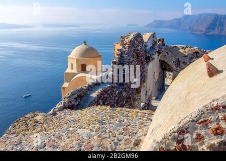 Griechenland. Santorini (Thira) Insel bei sonnigem Wetter. Kirche und alte Ruinen auf der Caldera in Oia. Panoramaaussicht auf das Meer Stockfoto