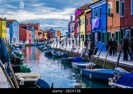 Burano, berühmte Fischerinsel in der Lagune von Venedig. Februar 2019. Bunte Häuser entlang eines kleinen Kanals mit Booten. Stockfoto