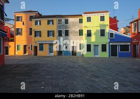 Orange, Senf, Limettengrün, Braun und Blau, einige der farbenfrohen Häuser von Burano, Venedig im frühen Morgenlicht Stockfoto