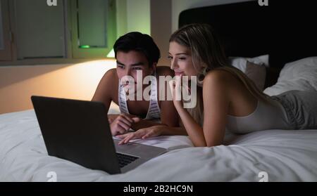 Junge Paare betrachten den Laptop zusammen Stockfoto