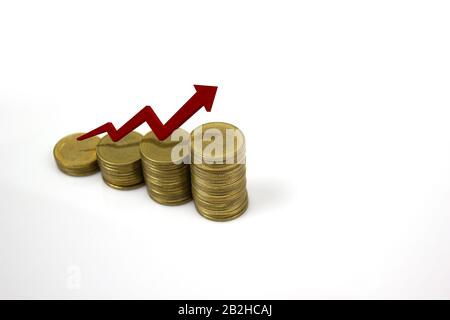 Wachsender Münzstapel mit aufsteigendem roten Pfeil auf weißem Hintergrund mit Leerzeichen rechts. Geschäfts- und Finanzkonzept. Stockfoto