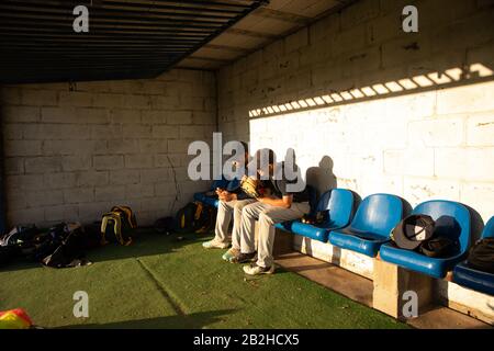 Baseballspieler diskutieren gemeinsam auf der Bank sitzend Stockfoto