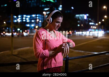 Frau mit Seitenansicht, die ihre Uhr vor dem laufen betrachtet Stockfoto