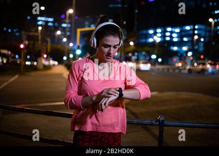 Frau mit Vorderansicht, die ihre Uhr vor dem laufen betrachtet Stockfoto