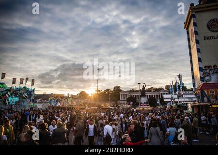 Die Sonne geht über das Oktoberfestgelände, Hunderte feiern das Bayerische Bierfest in München mit viel Essen, Bier und Spaß. Stockfoto