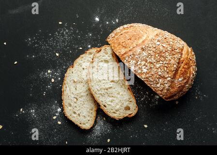 Frisch gebackenes traditionelles Brot, von oben auf schwarzem Grund angeschossen, mit Mehl bestreut. Stockfoto