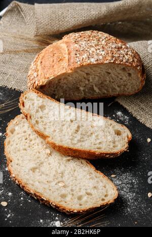 In Scheiben geschnittenes rustikales Brot zwischen ​​fresh und Weizenähren. Stockfoto