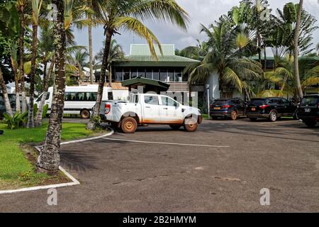 Geparkte Lastwagen und SUV vor dem Hoteleingang des Meridien Mandji am frühen Morgen in Port Gentil. Stockfoto