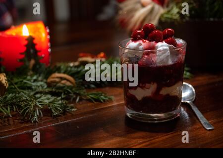 Ein veganes Dessert mit Schokolade, Sahne und Kirschen auf einem Tisch mit Weihnachtsdekoration Stockfoto