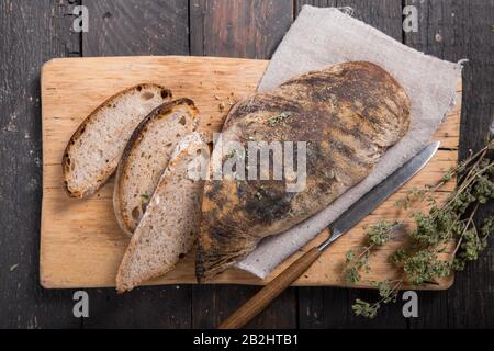 Frisches italienisches Ciabatta Brot mit Kräutern und Oliven auf Holzhintergrund, Draufsicht, Kopierraum. Stockfoto